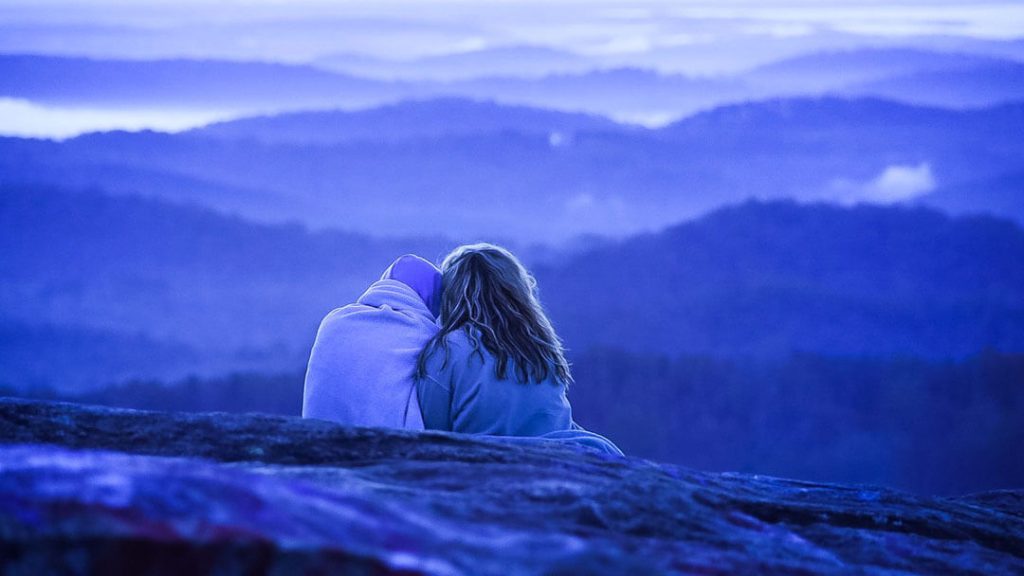 Couple assis l'un à coté de l'autre devant un paysage de montagne. Union, pacs.